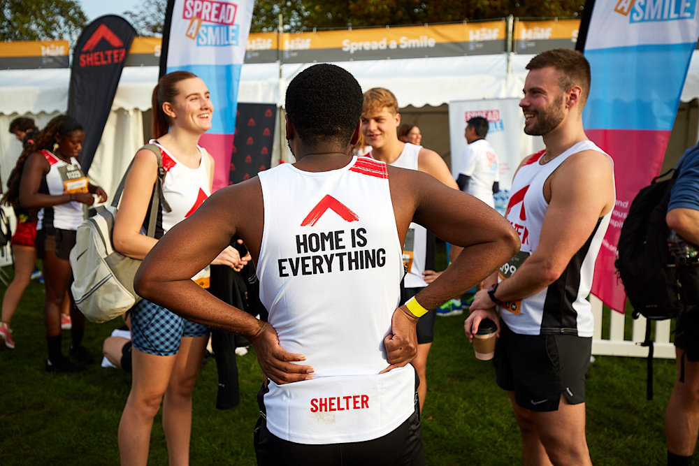 Four runners wearing Shelter vests stand in a circle chatting before the race.