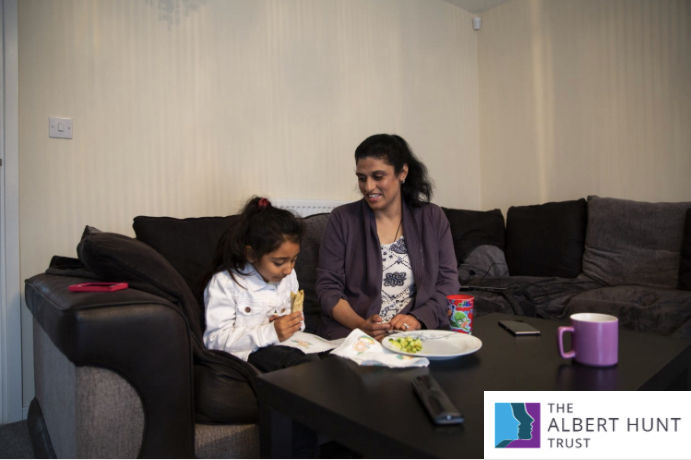 A woman and child eat a snack sitting on their sofa