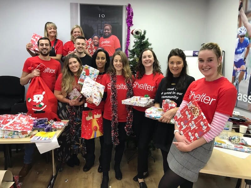 Team holding Christmas presents with Shelter T-shirts on