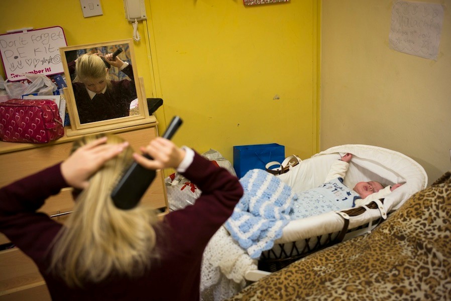 Girl brushing hair in front of mirror in a small room