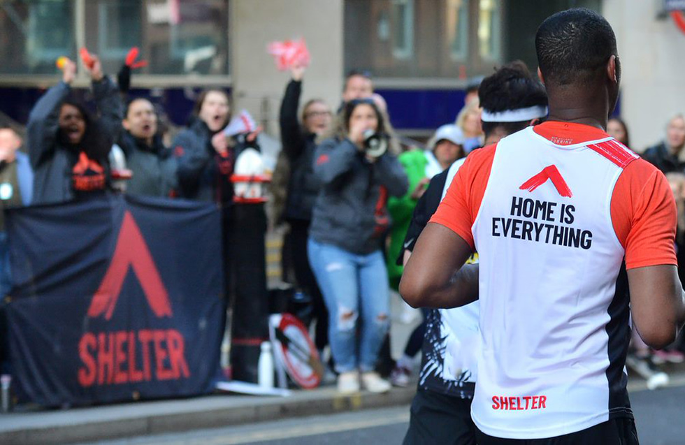 A man runs past a cheer point wearing a T-shirt with Shelter's slogan: Home is everything