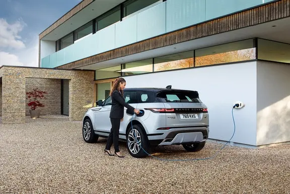 Woman plugging in a car charger to Range Rover Evoque
