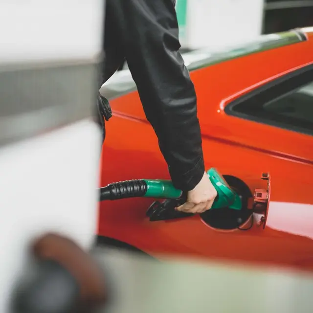 Person putting petrol into a red car.