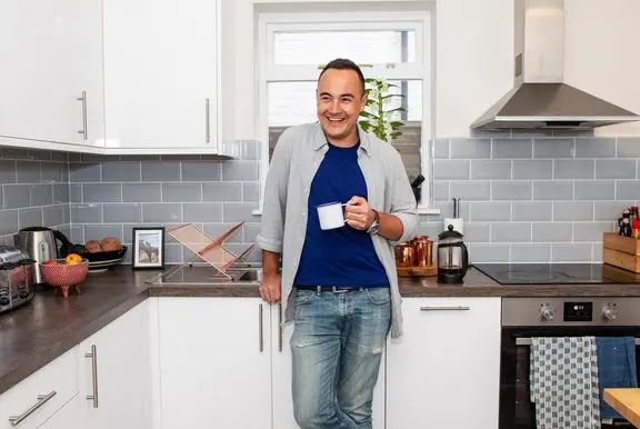 A Cazoo customer smiling in the kitchen after a successful delivery