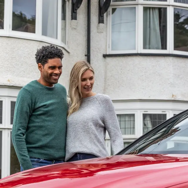 Happy couple looking at their new car from Cazoo