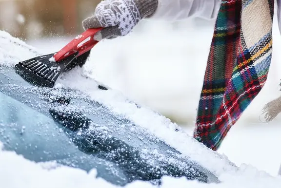 Person scraping snow off windscreen