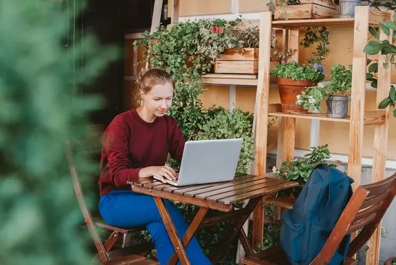 lady sat outside browsing cazoo on a laptop