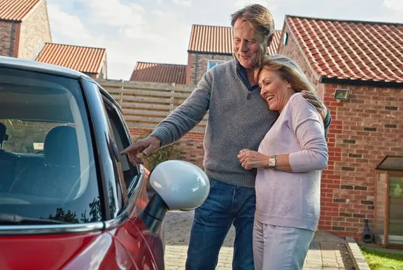 Happy couple looking at their new car