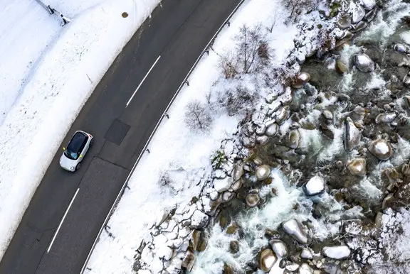 Birds eye view of a car driving in a snowy landscape