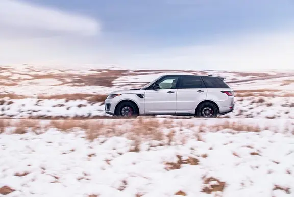 White SUV driving through a snowy landscape