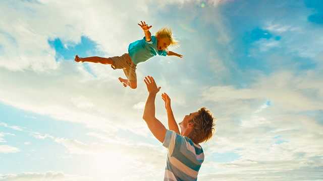 A man throwing his child in the air, and catching him