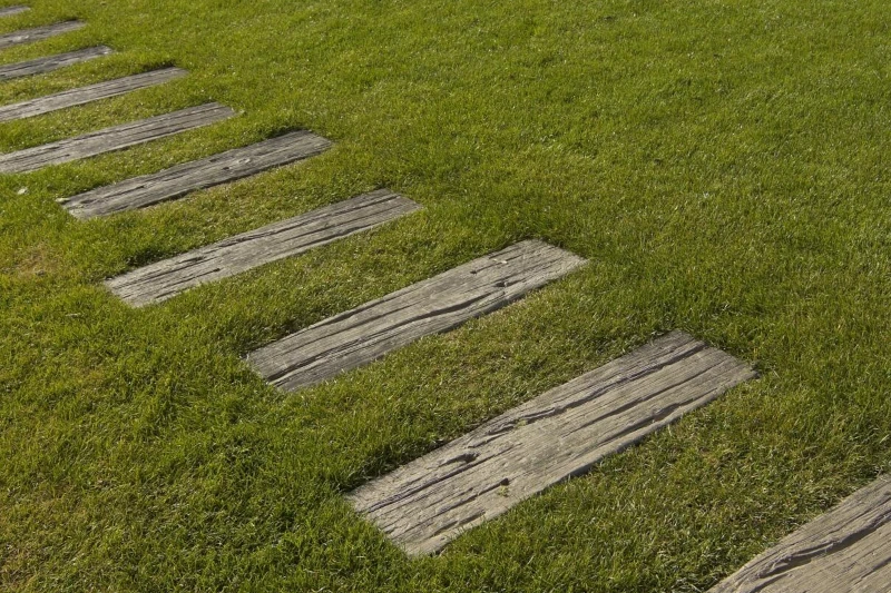 Gehwegplatten aus Holz, die auf dem Rasen im Garten als Weg platziert sind.