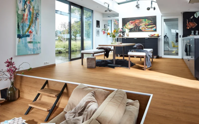 Moderner, lichtdurchfluteter Wohnraum mit Holzboden, Kunst und großen Fenstern