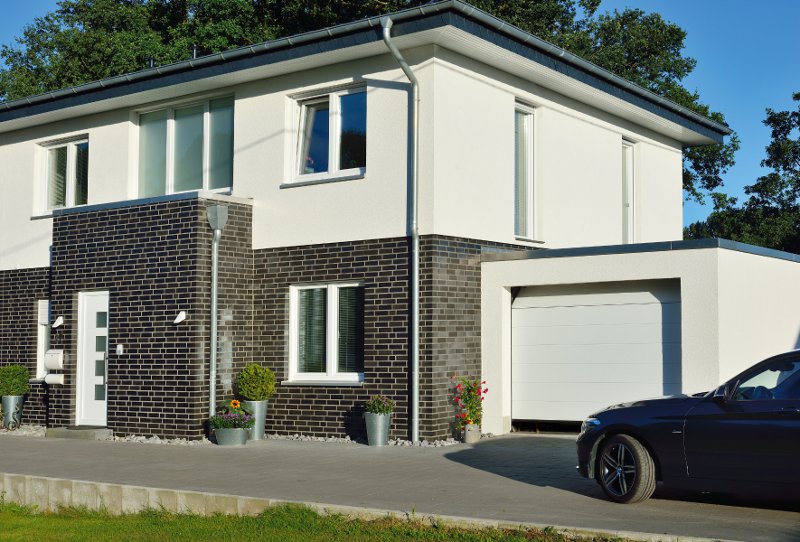 Mehrfamilienhaus in weiß und Backstein mit Garage und Auto davor