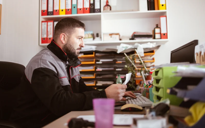 Vier Personen, die in einem Büro an einem Tisch stehen. Im Raum und auf dem Tisch befinden sich Kartons.