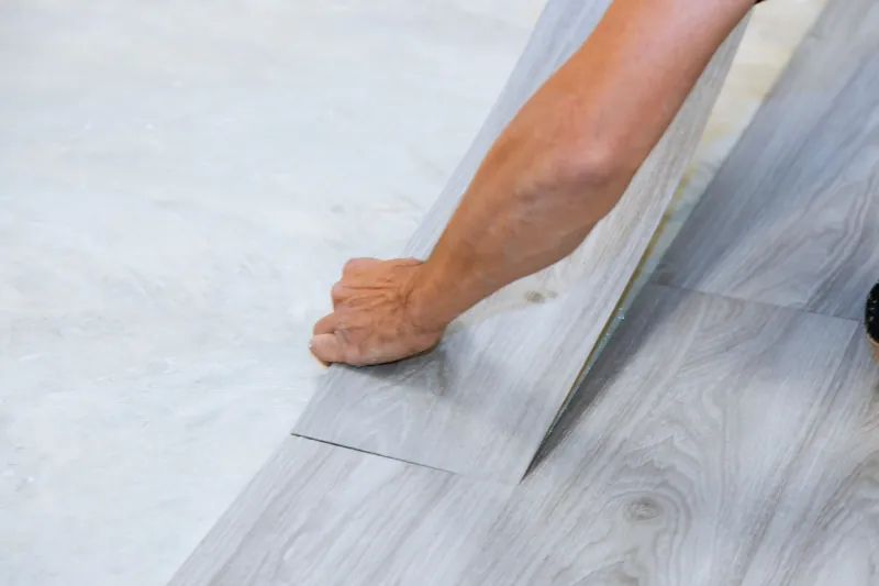 Handwerker verlegt graues Klick-Vinyl auf dem Boden