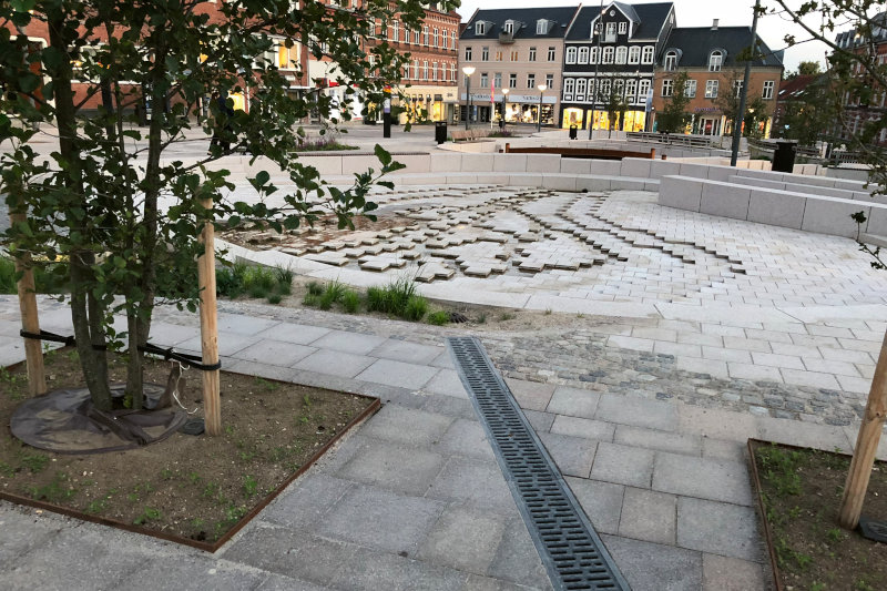 regnerische Straße mit Ausschnitt aus einem Entwässerungssystem in der Erde
