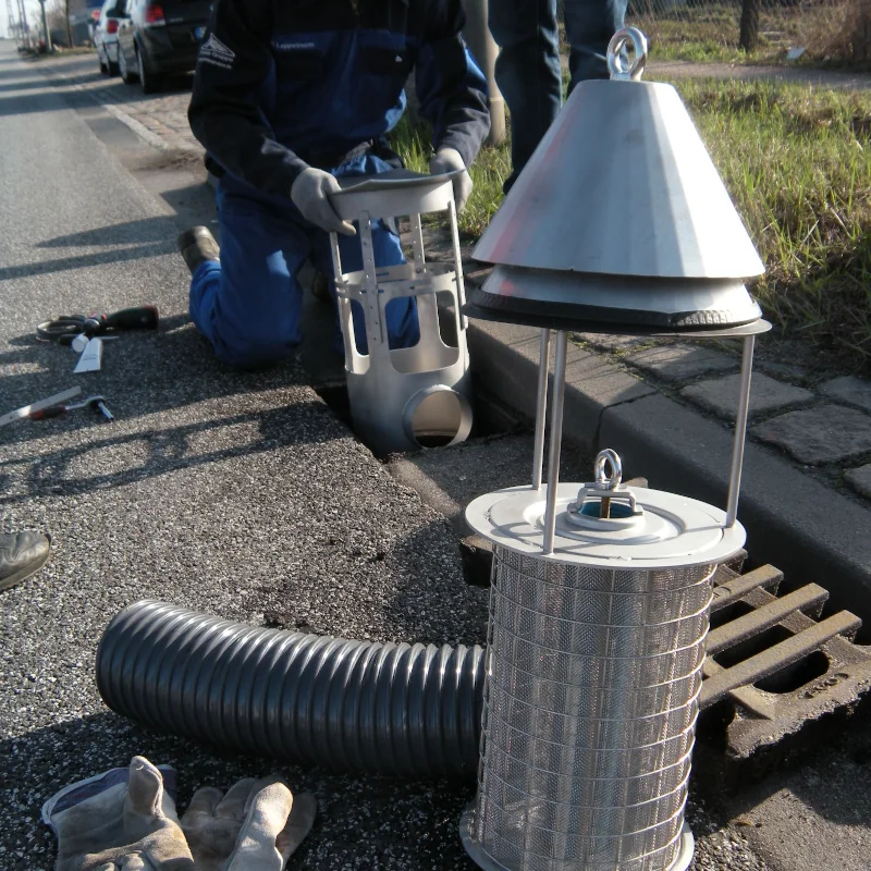 Arbeiter installiert Filtergerät in Straßenkanal.