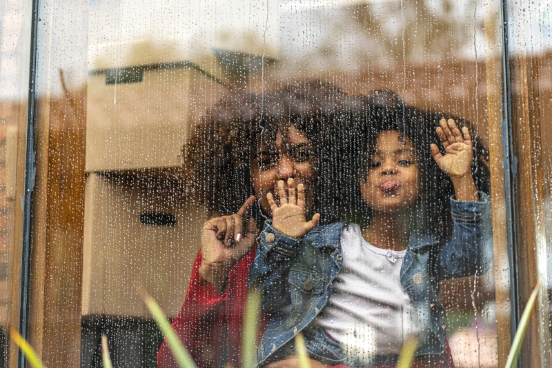 Eine Frau und ein Kind an einer Fensterscheibe. Im Hintergrund einige Umzugkartons.