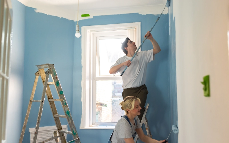 Ein junges Paar richtet seine erste gemeinsame Wohnung ein und streicht die Wände blau