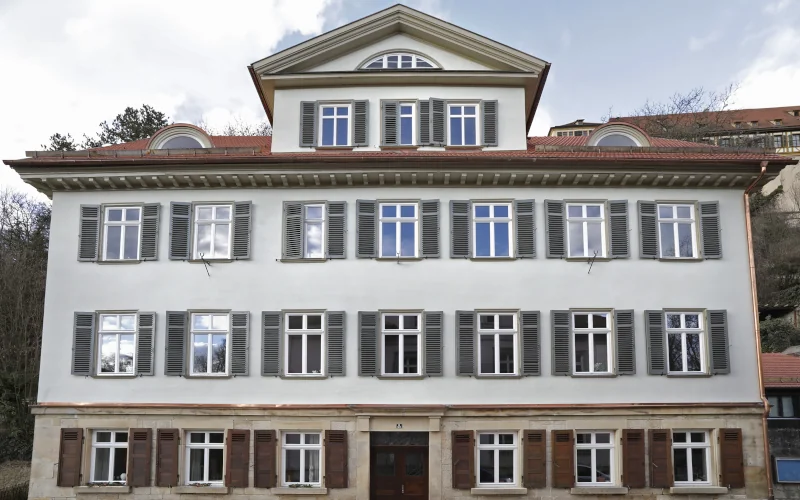 großes weißes Gebäude mit Fensterläden und Satteldach