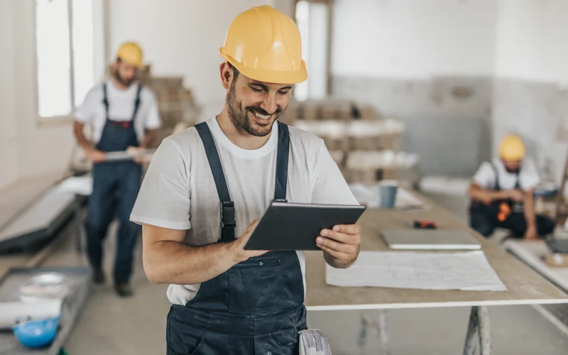 Handwerker steht mit Tablet auf einer Baustelle