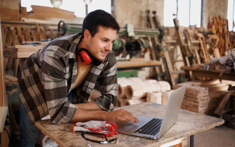 Tischler mit Laptop im Lager
