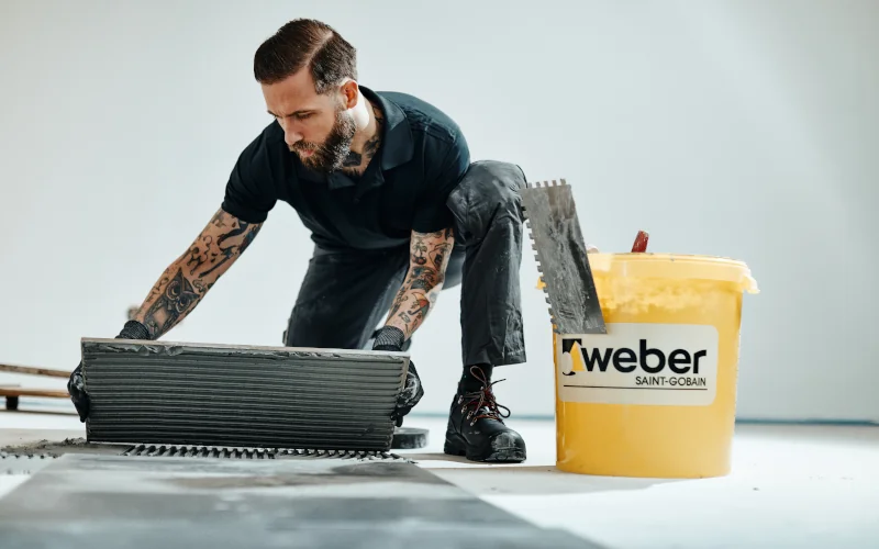 Handwerker verlegt Fliesen mit Produkten von SG Weber