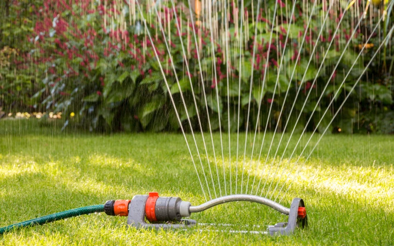 Rasensprenger bewässert grünen Rasen im Garten.