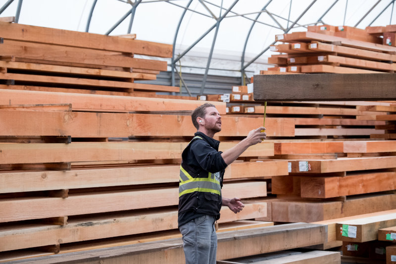 Mitarbeiter prüft Holzlatten im Lager