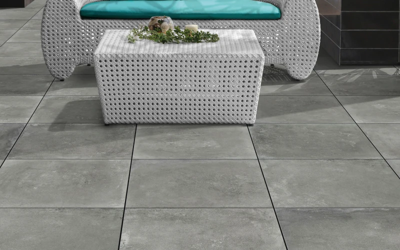 Terrasse mit hellgrauen Platten und Sitzmöbeln