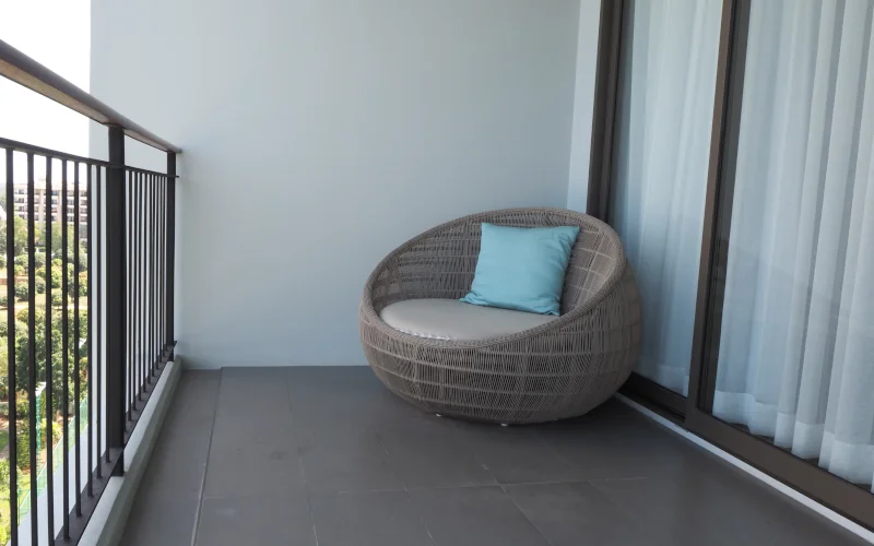 Ein gemütlicher Sessel mit Kissen auf einem modernen Balkon.