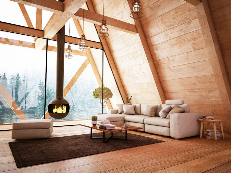Dachgeschoss aus Holz mit großer Fensterfront und einer Sitzgruppe und Kamin