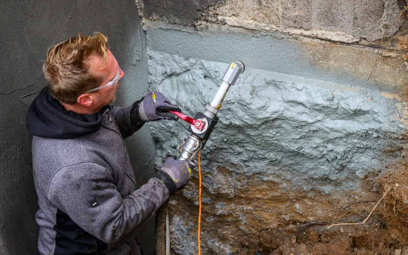 Bauwerksabdichtung ZR Turbo XXL wird mit einer Sprühpistole auf eine Hauswand aufgetragen