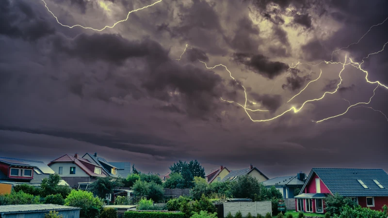 Dunkle Wolken und Blitze über einer Wohnsiedlung.