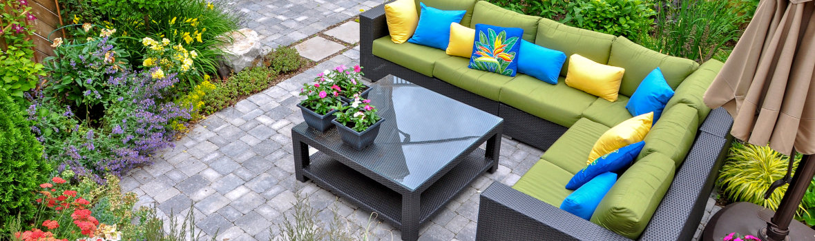 Terrasse mit Sitzlounge und Beistelltisch u7mgeben von Blumen und Pflanzen