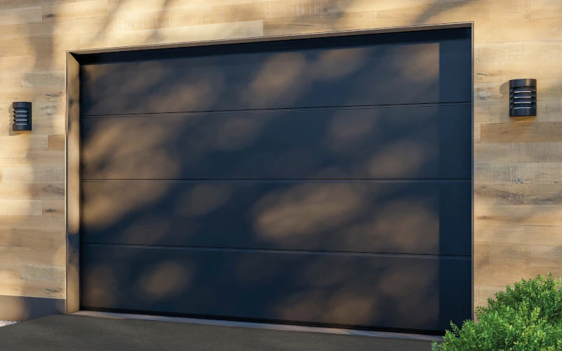 Dunkelgrauen Platten auf einer Auffahrt zu einer Garage in mediterraner Optik mit dunklem Garagentor