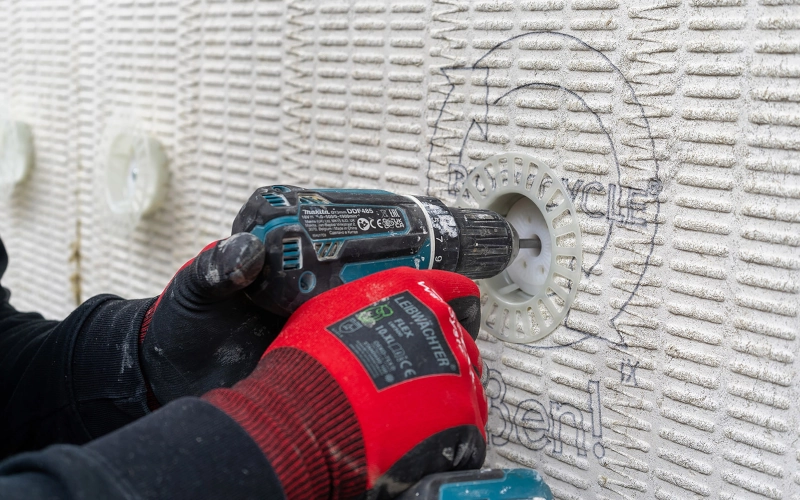 Dübel wird mit einer Akkubohrmaschine in der Wand befestigt