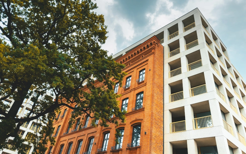 Front eines Mehrfamilienhaus mit einer roten Backsteinfront und weißen, überdachten Balkons
