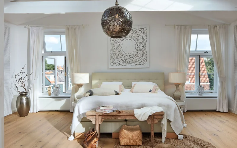 helles Schlafzimmer mit einem Doppelbett und metallischen Akzenten im Raum verteilt