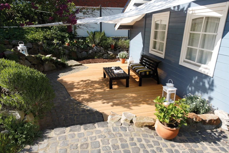 blaues Haus mit Terrasse ausgestattet mit Terrassendielen aus Lärche