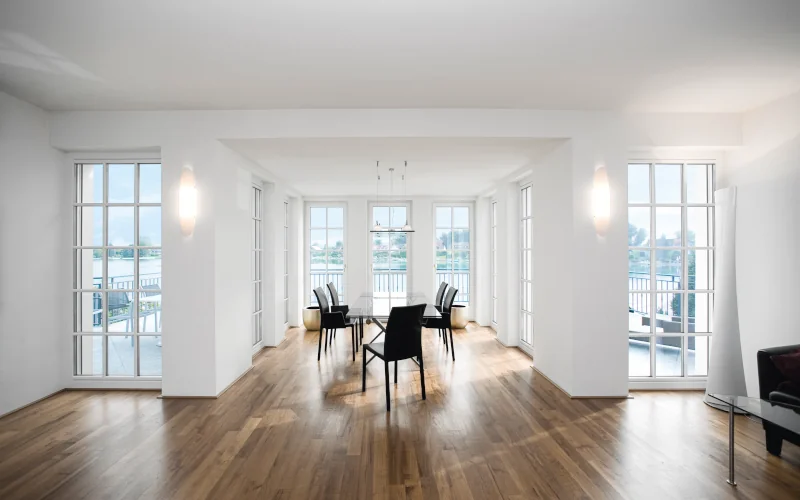 großes Zimmer mit vielen Fenstern und Stühlen in der Mitte