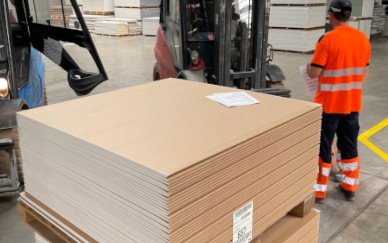 Palette mit Schallschutzplatten in einer Logistikhalle. Davor steht ein Gabelstapler und ein Logistikmitarbeiter