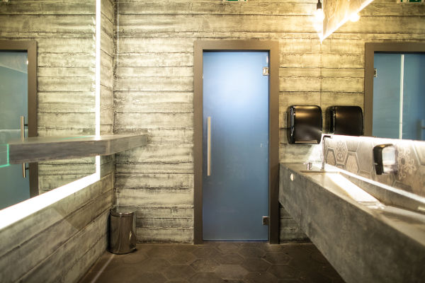 Moderne öffentliche Toilette mit Betonwänden und blauen Türen.