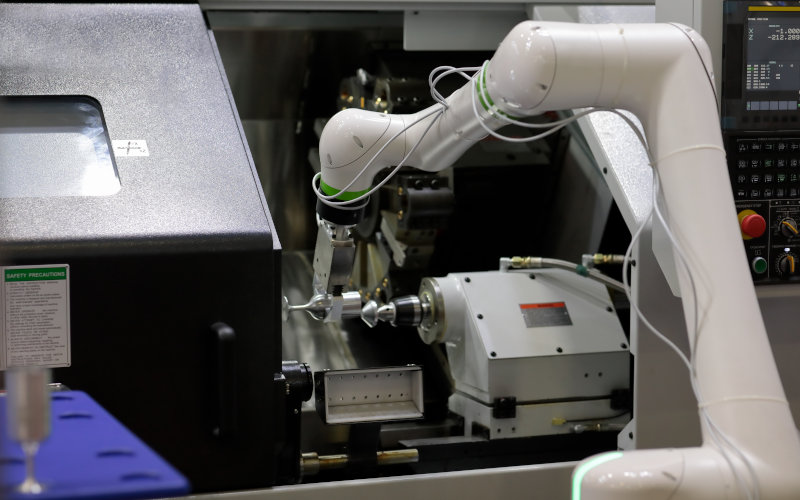 ein weißer Roboterarm baut an einem Gegenstand