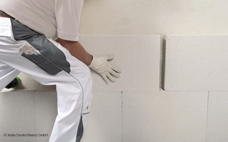 Handwerker bringt weiße Dämmplatten auf einer Wand an