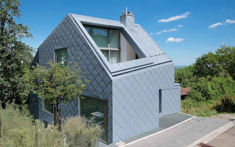 Haus mit grau-blauer Metallfassadenbekleidung