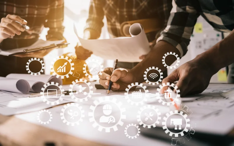 Team arbeitet an Bauplänen, überlagert von digitalen Prozesssymbolen