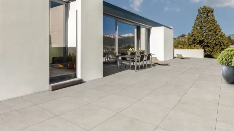 Terrasse mit hellgrauen Platten und Sitzmöbeln