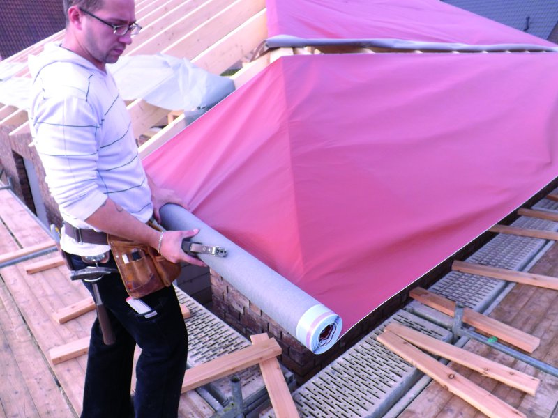 Dachdecker verarbeitet Baumaterial auf dem Dach